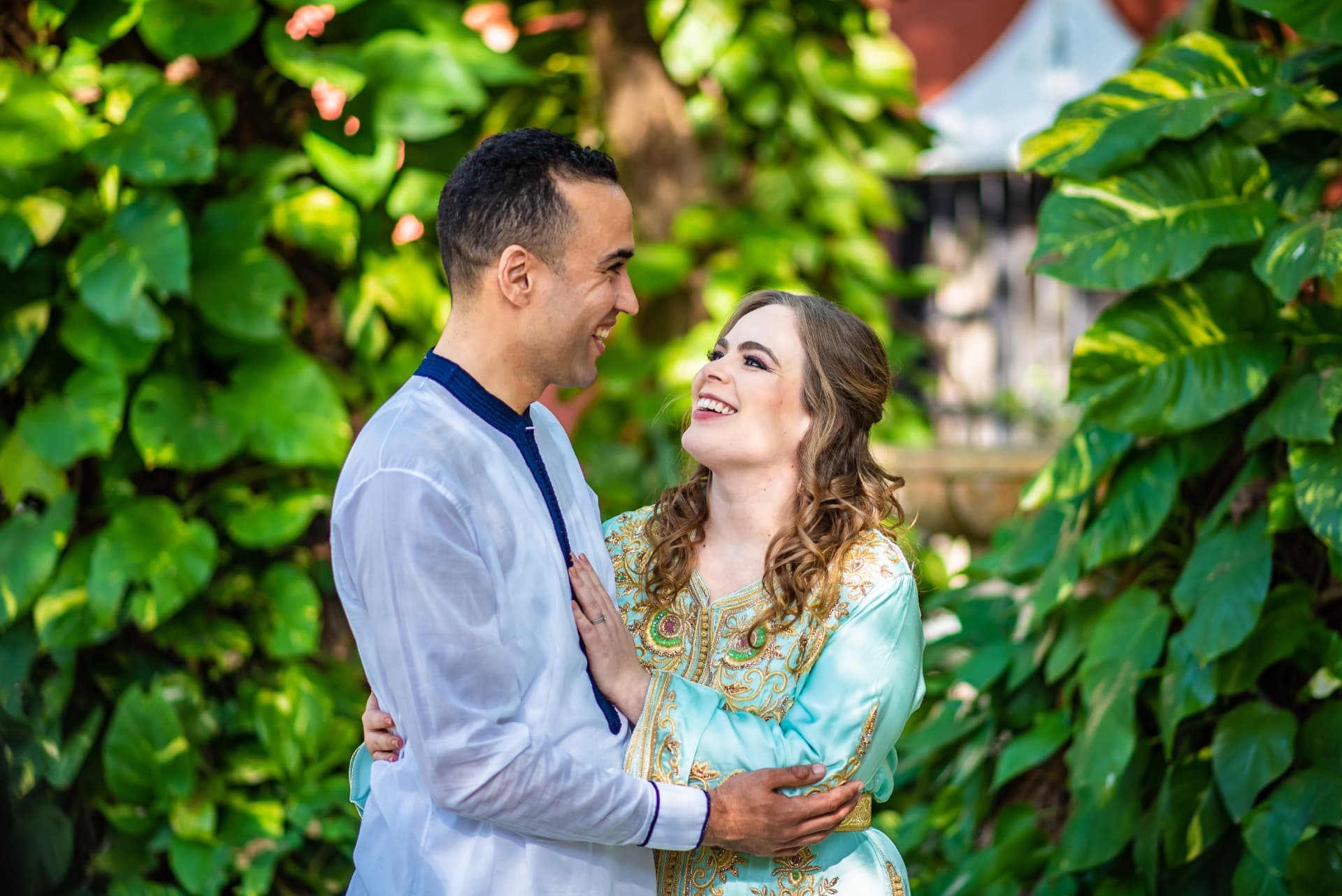 Pareja con atuendo tradicional marroquí abrazada en un jardín tropical