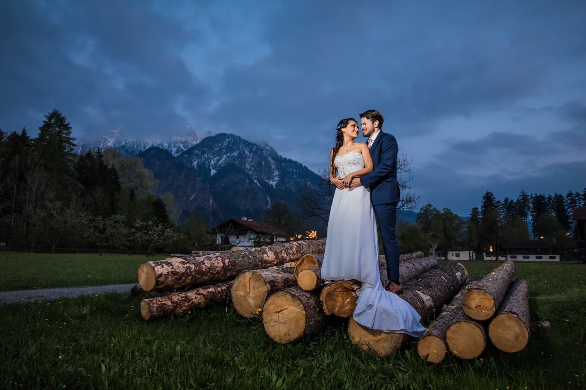 Pareja de novios ante las montañas de Baviera al anochecer, sesión postboda