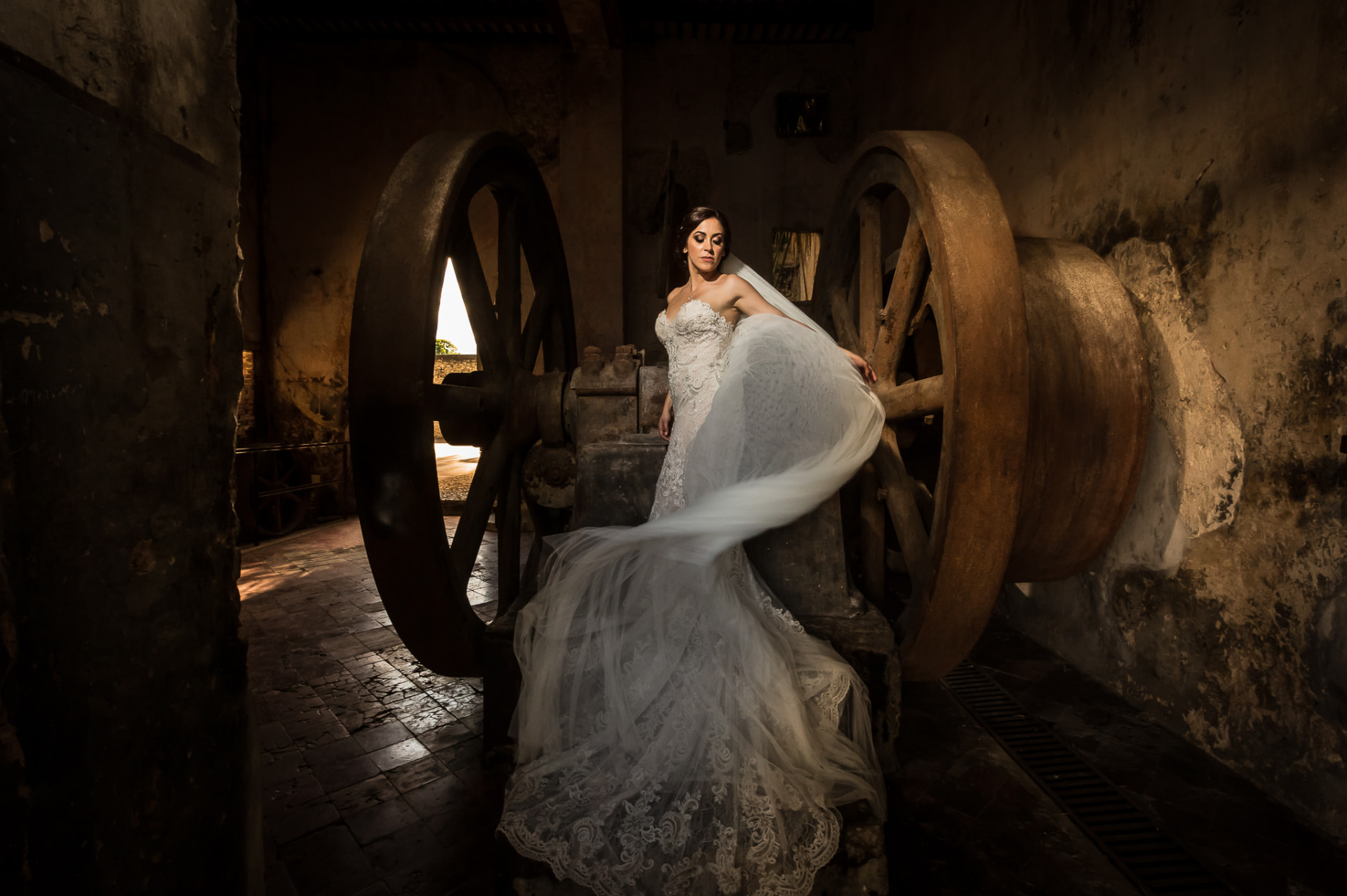 Retrato editorial de novia entre maquinaria histórica y luz cálida