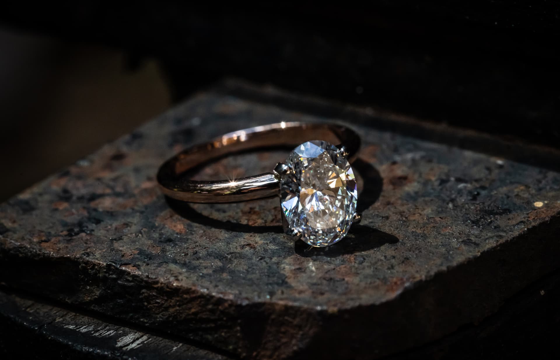 Anillo de compromiso con diamante ovalado sobre superficie rústica, detalle de boda