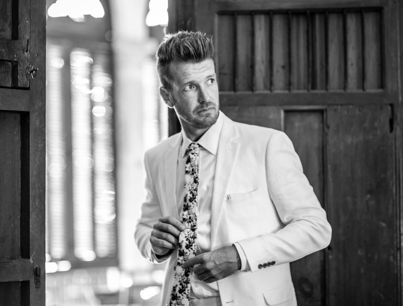 Retrato editorial del novio con traje claro antes de la boda
